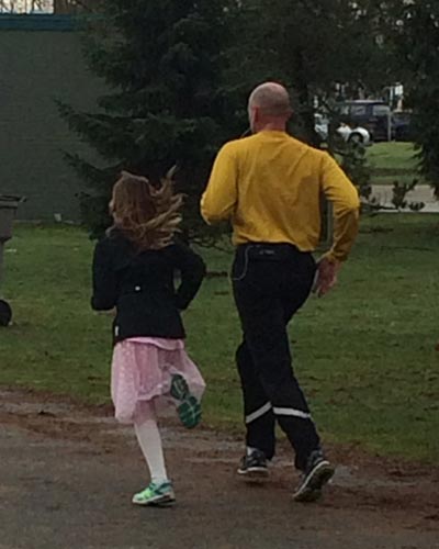 Rear view of a father and daughter running together.