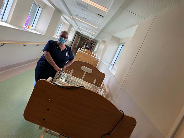 a health care professional stands in a hallway next to the newly assembled hospital bed