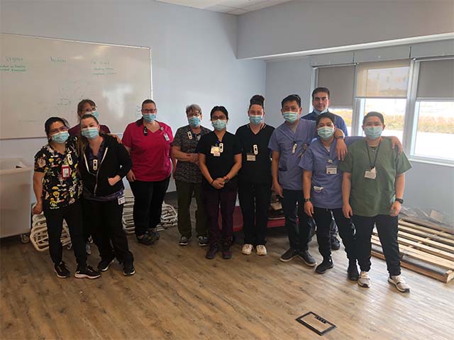 a group of health care professionals pose with masks on after completing the new bed building task!