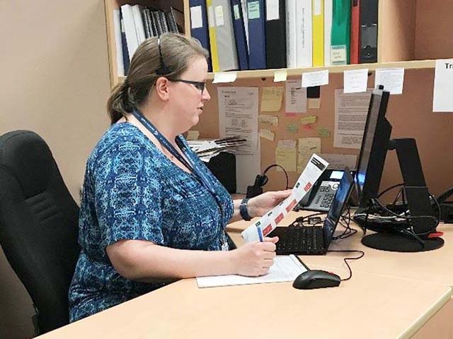 a woman in scrubs answers the phone while looking at a paper