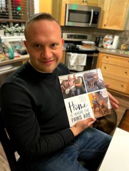 A man holding a personalized calendar titles "home is where the paws are" 