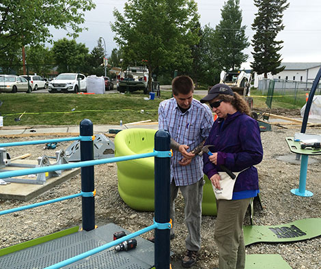 Two people assembling playground equipment.