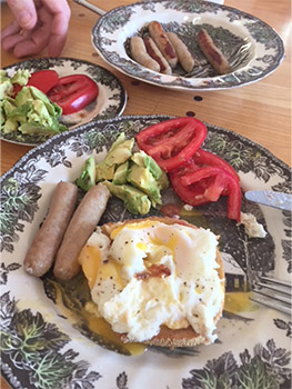 Meal with salad, sausages, avocado and tomatoes.