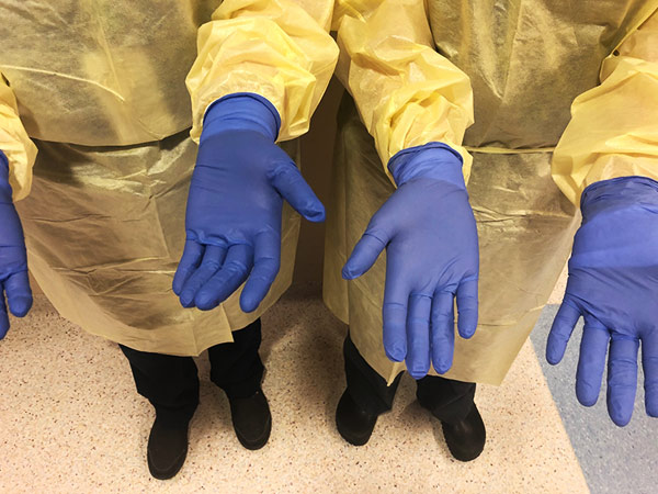 Two nurses show their gloved hands. 