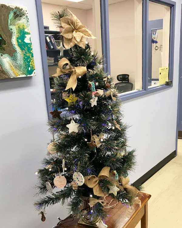 A Christmas tree with gold and white decorations is in front of an office. 