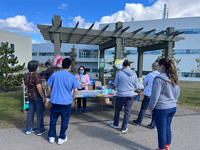 a group of people stand in a line waiting to receive a gift from the NH booth 