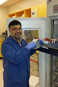 Man in lab coat shows tray of blood products. 