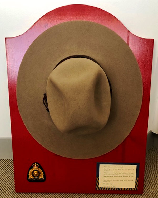 A plague on red wood features a mounted police officer's hat and badge, and an inscription.