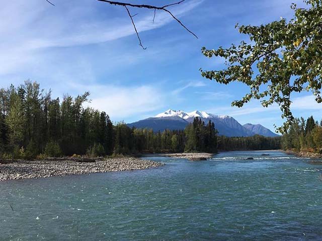 a river with a rocky shoreline with a mountain in the background