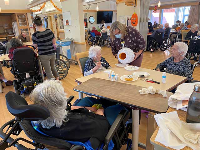 people in wheelchairs decorating pumpkins