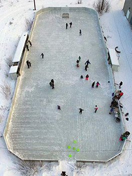 Aerial photo of an outdoor ice rink with people skating on it.
