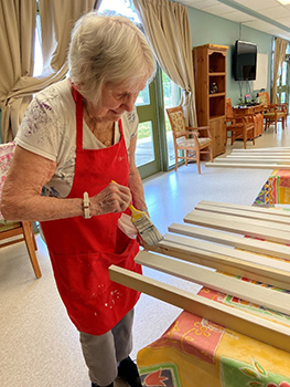 Elderly woman painting pieces of wood