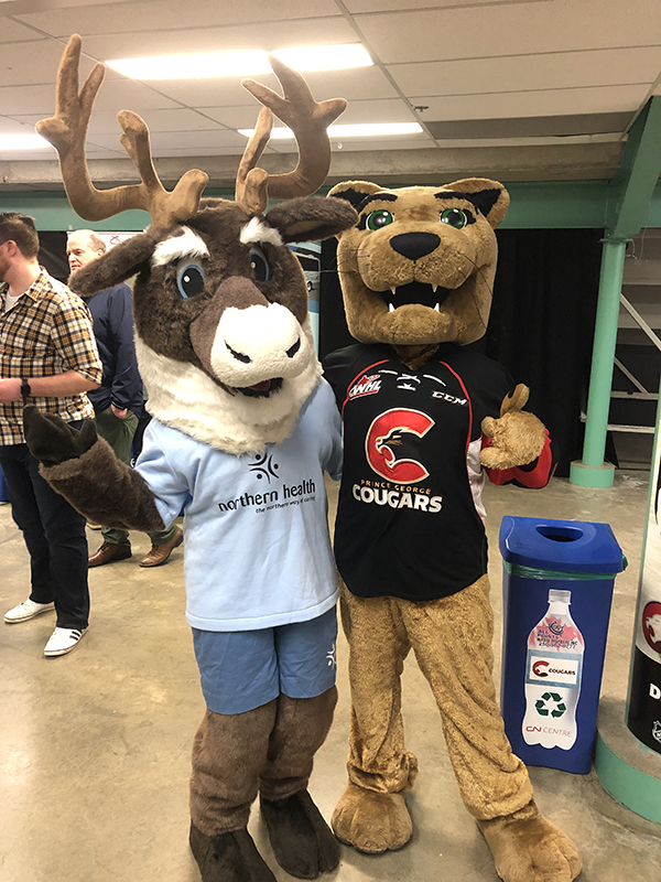 Spirit the caribou mascot and Rowdy the cougar mascot standing with arms around each other.