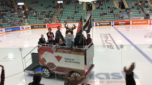 Spirit mascot riding on a zamboni at a hockey rink.