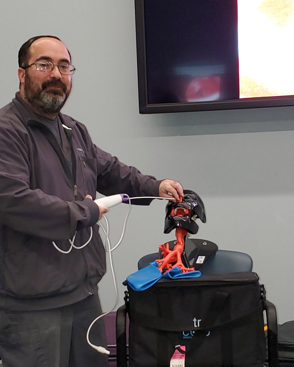 A man demonstrates using the scope of a dummy. 