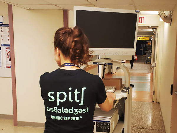 A female wheels medical equipment down a hallway.  