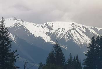 a large mountain in terrace with white snow peaks and fog