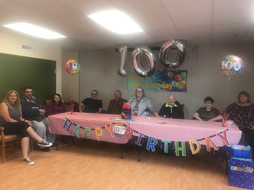 People celebrating a 100th birthday sitting around a large table.