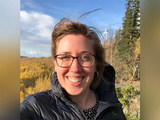 a woman with brown hair smiles into the camera selfie style