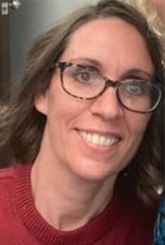 a woman with brown, wearing a red sweater, smiles into the camera