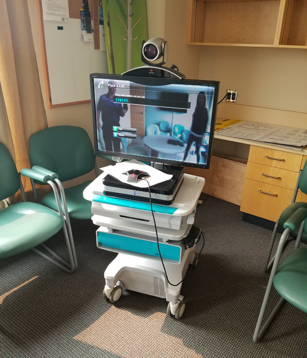 A white telehealth cart on wheels with a monitor and camera attached on top..