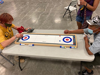 Two men sitting down playing a table game.