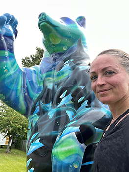 Woman standing next to bear statue.