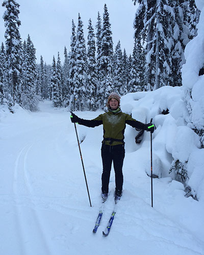 Woman stopped and facing the camera while out cross country skiing after a recent snowfall