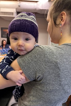 Woman holding baby wearing a purple toque