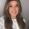 Woman with long hair smiles into the camera with a plain background