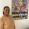 Woman stands next to a colourful piece of artwork that reads "Small Steps every day"