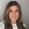 Woman with long hair smiles into the camera with a plain background