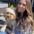 Young woman with long hair holds small white dog