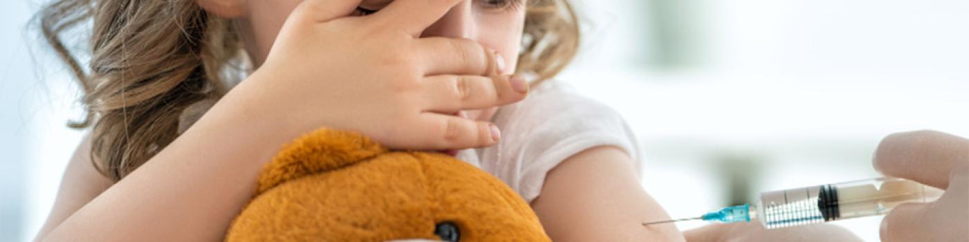 Child covers eyes while getting needle in her arm