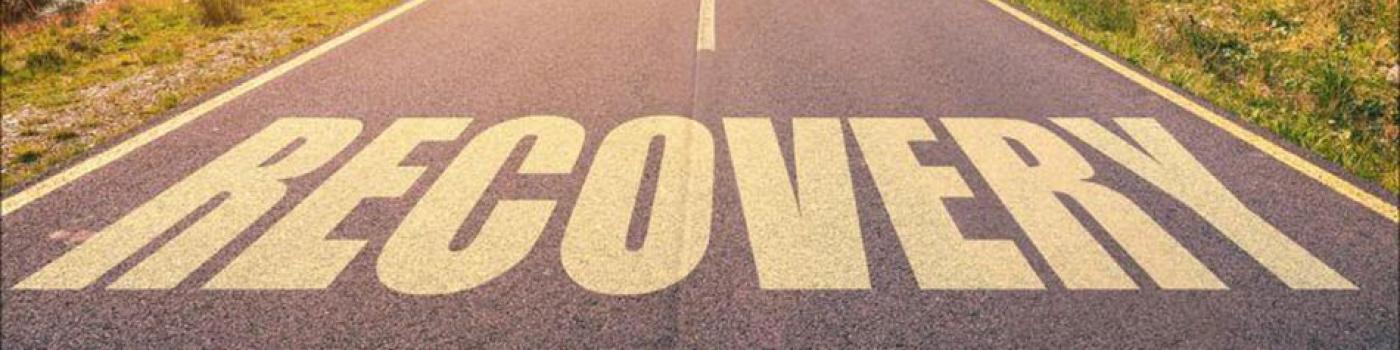 Recovery written in Yellow paint on a paved road