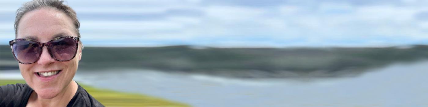 Woman wearing sunglasses in front of blurred background.