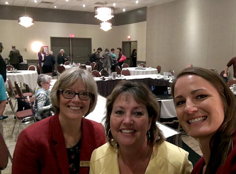 From left to right, Cathy Ulrich, NH CEO; Colleen Nyce, NH Board Chair; and Julianne Kucheran, Community Consultant, Urban Matters smile into the camera as a meeting breaks behind them.