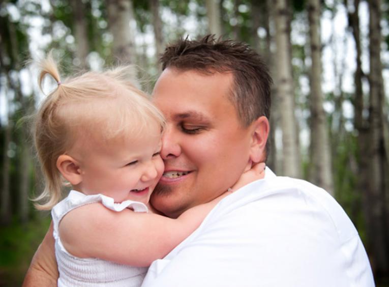 A dad holding his smiling daughter.