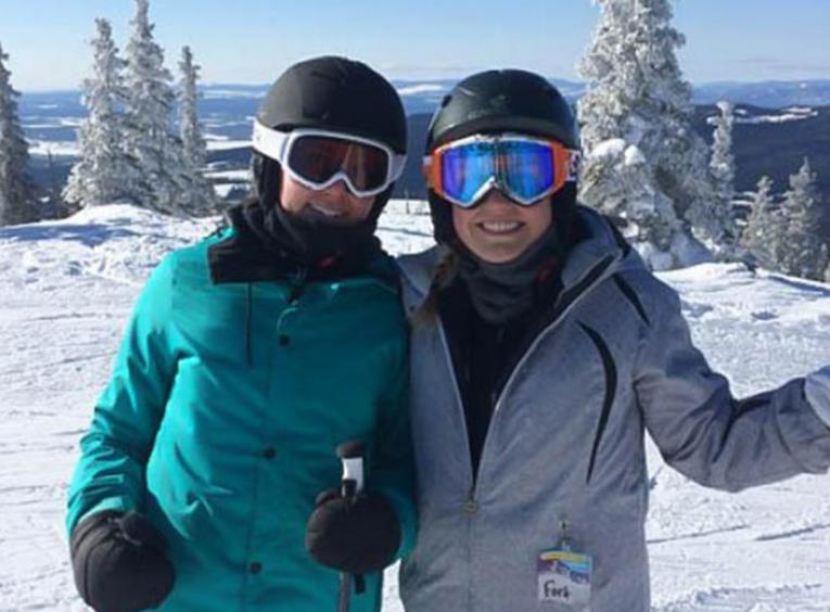 Two women posing while downhill skiing