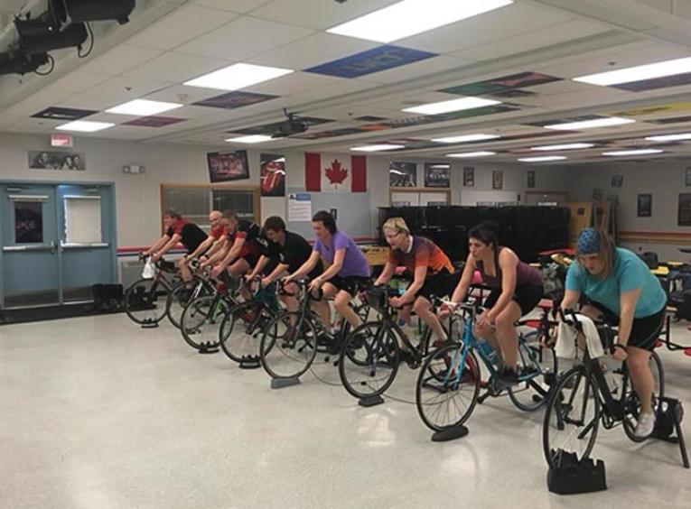 Group of people cycling indoors.