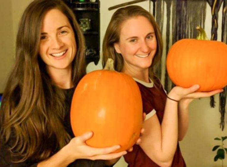 Two women holding pumpkins