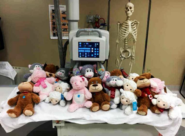 A hospital bed is covered in stuffed animals. 