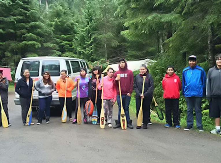Youth group on forest roadside with paddles.