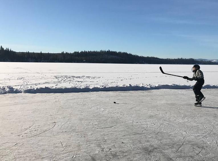 boy playing hockey on frozen lake.