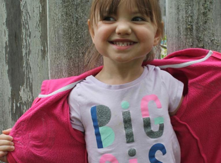 Young girl wearing a big sis t-shirt.