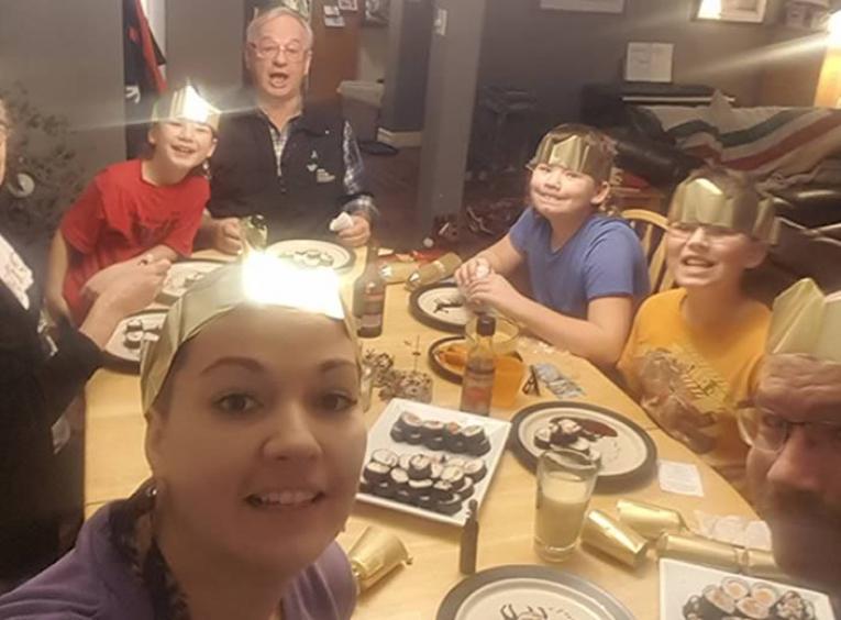 7 people around a dinner table wearing paper crowns.