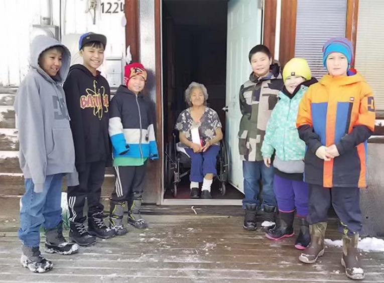 Group of kids and elder standing outside on a house deck in winter.
