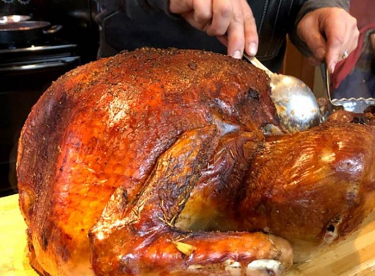 A man carves a turkey on a cutting board.