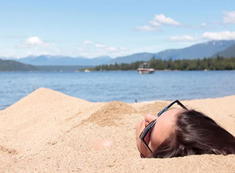 Girl laying in sand on a beach.