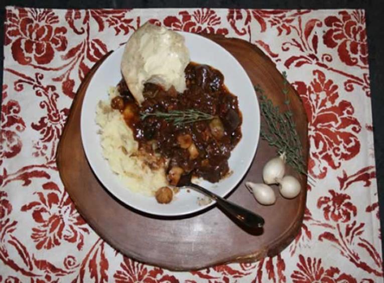 Plate of stew on table with table settings.